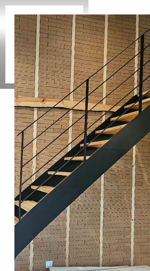 Escalier avec rambarde m&eacute;tallique noire et mur en briques apparentes