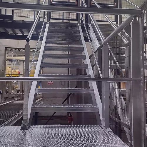 Escalier métallique dans un entrepôt avec garde-corps et plateforme d’accès