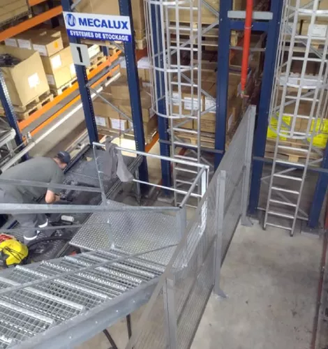 Travailleurs installant un escalier métallique dans un entrepôt avec structures en acier