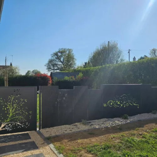 Portail en métal décoratif avec motif d’arbre et jardin soigné