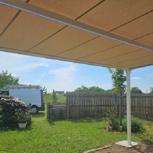 Auvent moderne avec toile tendue, vue sur le jardin et clôture en arrière-plan