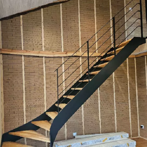 Escalier avec rambarde métallique noire et mur en briques apparentes