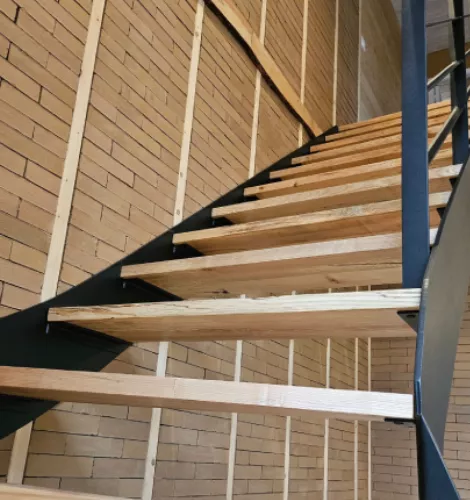 Détail de l’escalier métallique noir avec structure en bois brut