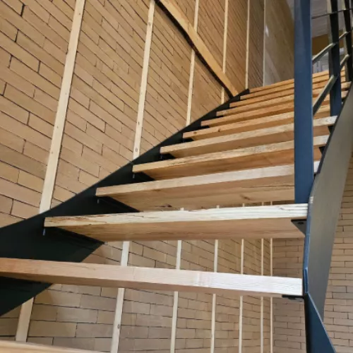 Détail de l’escalier métallique noir avec structure en bois brut