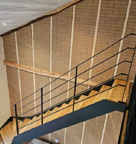 Escalier métallique noir avec rambarde et mur en briques apparentes