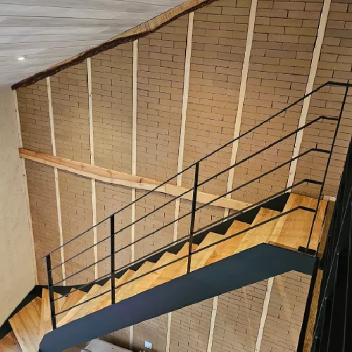 Escalier métallique noir avec rambarde et mur en briques apparentes